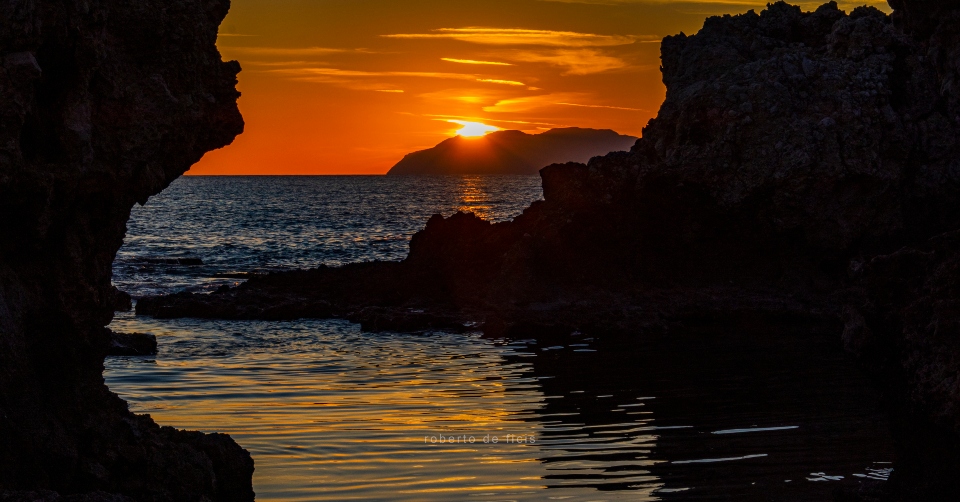 Sai dove è possibile ammirare questo Tramonto Rosso tra gli scogli e il sole che accarezza le Isole?