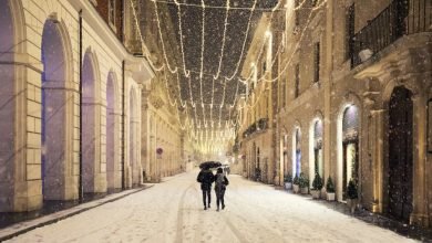 Abbracciati sotto la neve nel centro storico di L'Aquila