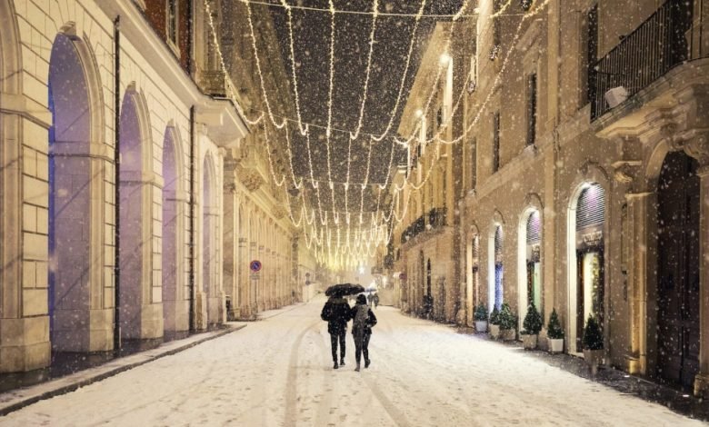 Abbracciati sotto la neve nel centro storico di L'Aquila